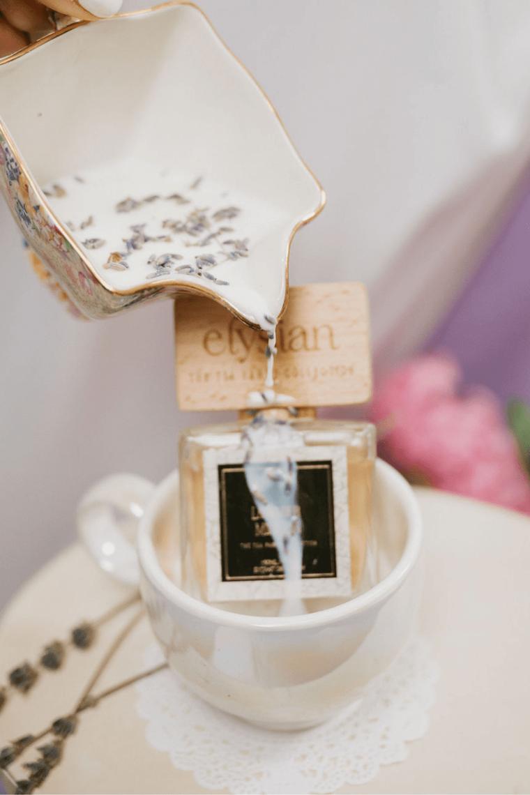 Lavender being added to a cup of tea beside a bottle of Lavender Milk Tea